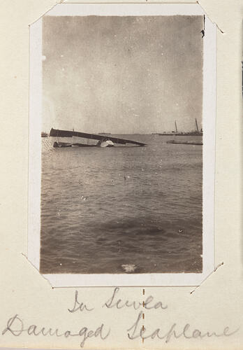 Plain sinking in sea water, ships in distant background.