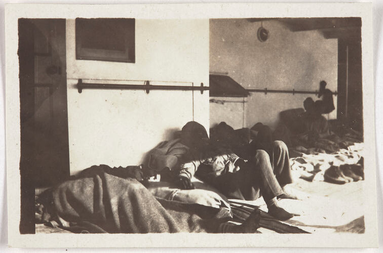 Five men sleeping in on the deck of ship.