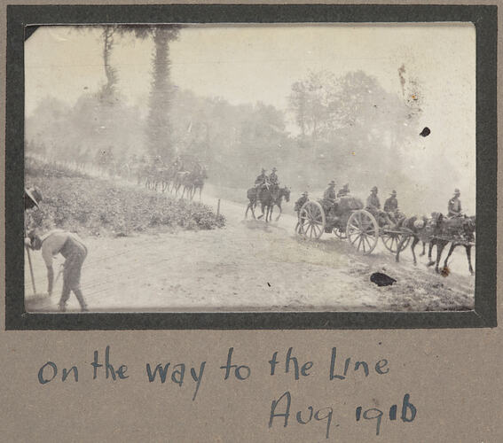 Convoy of servicemen on horses and horse drawn carts on a dirt road.