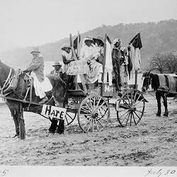 Horse-drawn wagon carrying a number of people dressed in 'black face'.