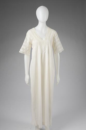 White night dress with V-neckline. Elbow-length sleeves and upper bodice are made from a continuous plank of f