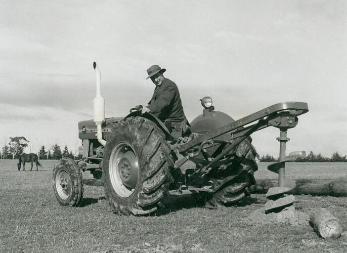 Man operating a Post Hole Digger attached to a tractor.