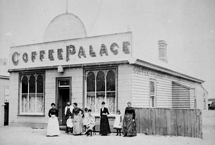 Group of people in front of the 'Coffee Palace', a weatherboard building.