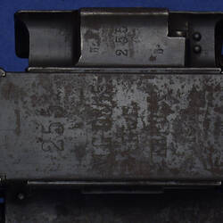 Detail of black rusted metal gun. Has stamped numbers and text.