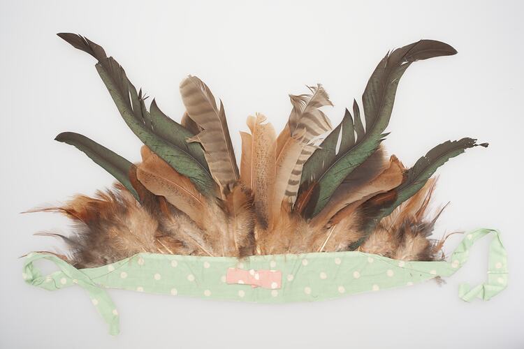 Feathered headdress. Brown and green feathers mounted in a green and white spotted band.