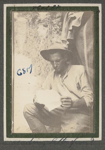 Soldier with hat on reading a letter.