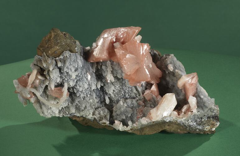 Grey rock with pink crystals on one surface.