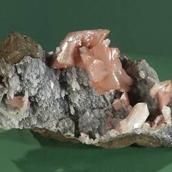 Grey rock with pink crystals on one surface.