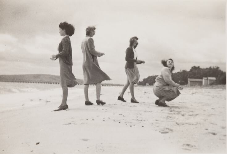 Four teenager girls feeding gulls on a beach.