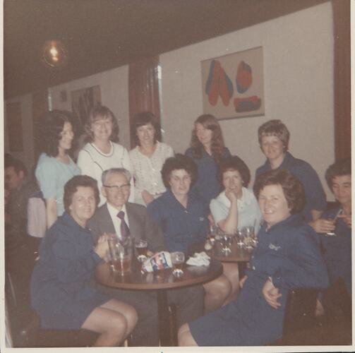 Women gathered around man at dinner table.