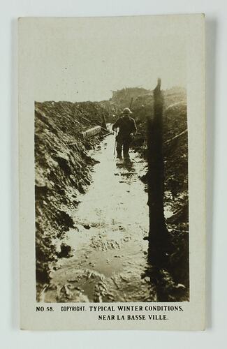 Servicemen in muddy trench.