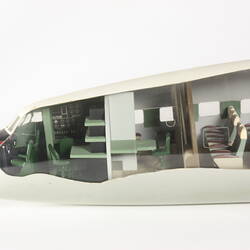 Model plane, front section with cut-out side exposing miniature green cockpit interior and passenger seats.