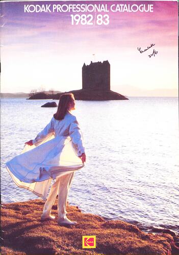 Cover page with a woman standing by some water, castle in background.