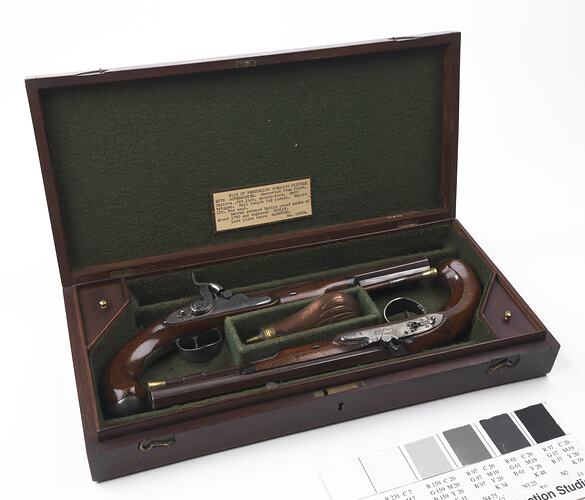 Wooden case, green lining. Contains two pistols.