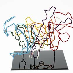 Red, orange, yellow, green, blue, purple and white coloured wires mounted on a black wooden base.