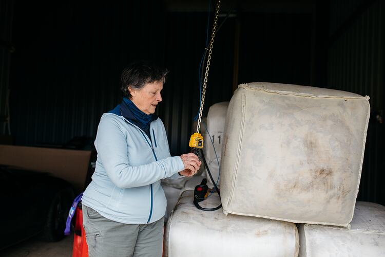Woman with lifting equipment and wool bales.