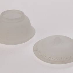 Opaque glass round spice container (upside down) with lid beside it. Container is narrower at base.