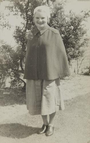 Young smiling woman wearing nurses' uniform of  young woman wearing uniform of cape, cap, dress, lace-up shoes