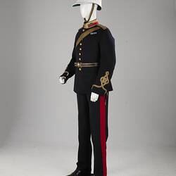 Navy officer's uniform with gold at cuff, epaulettes, belt. Brass buttons. Red/gold collar. White helmet.