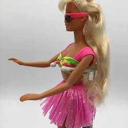 Blonde Barbie doll. Wears pink strapped multi-coloured bikini top and pink skirt and sunglasses.