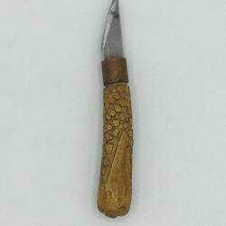Knife with carved wooden handle and small blade.