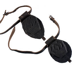Two black horse shoe soles with straps.