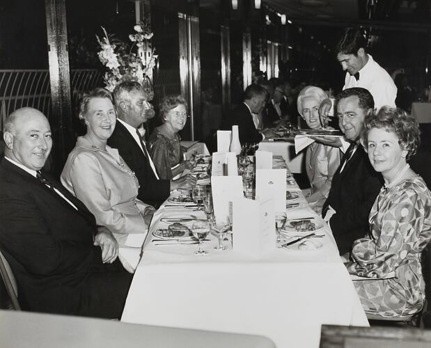 Men and women in formal dress sitting around a dinner table at a Massey Ferguson's social function.