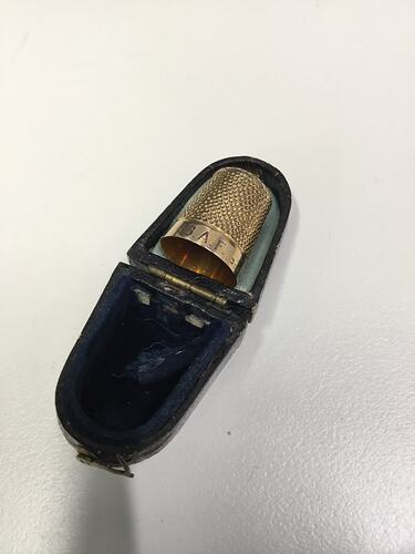 Gold thinble with engraving in box.