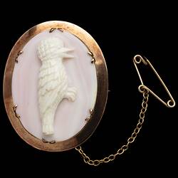 Pink oval shell cameo kookaburra brooch in a 9ct plain gold setting. Gold chain and pin.