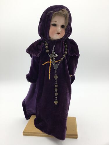 A doll dressed as an abbess in long purple robes