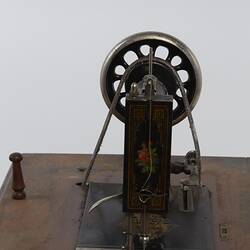 Detail sewing machine fitted to a metal frame with a wooden bench.