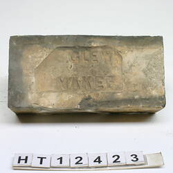 Discoloured white, rectangular and worn machine pressed brick. Maker's name stamped in frog.