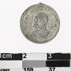Round medal with male portrait bust, text around.