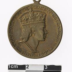 Round medal with profile of a crowned woman, text surrounding.