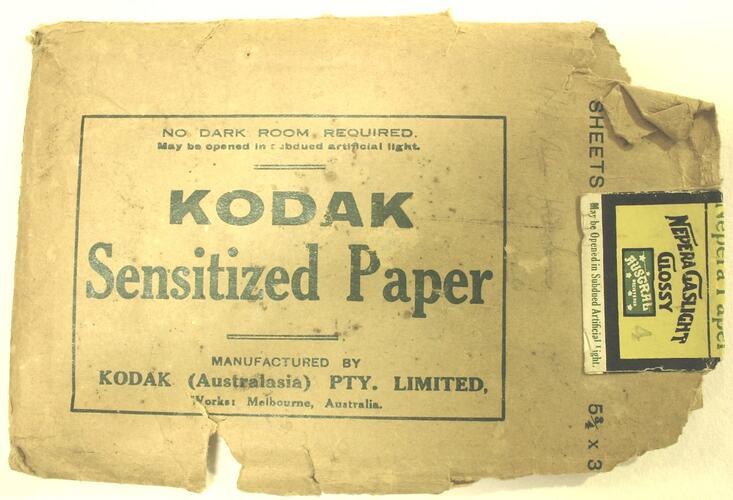 Torn brown paper wallet used to hold negatives. Brand name printed in green ink. Sticker at one end.