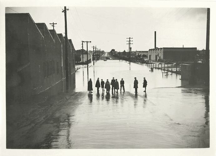 Nine people standing on wet street.