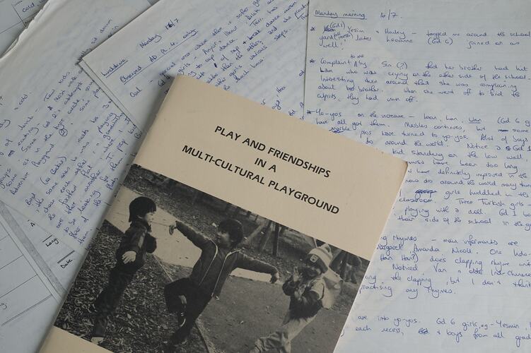 Handwritten pages spread out with a booklet on top featuring children at play.