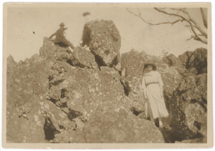 Three people on rocky landscape.