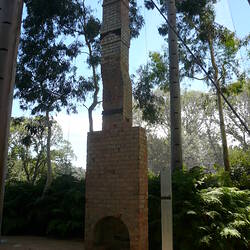 Red brick chimney reassembled in outdoor settting.