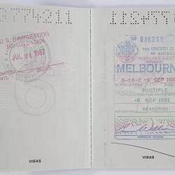 Open passport, white pages and black printing. Stamped. Hole punched number along edge.