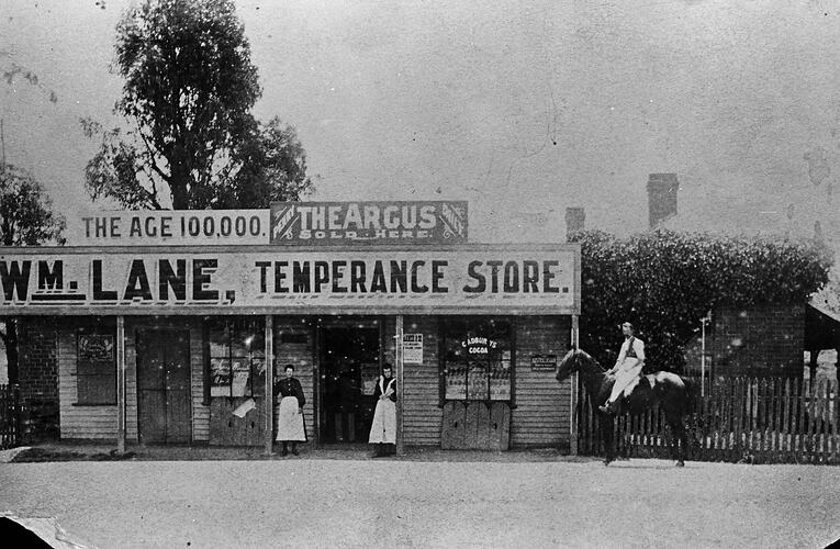 Staff outside a store. Man on horse at right.