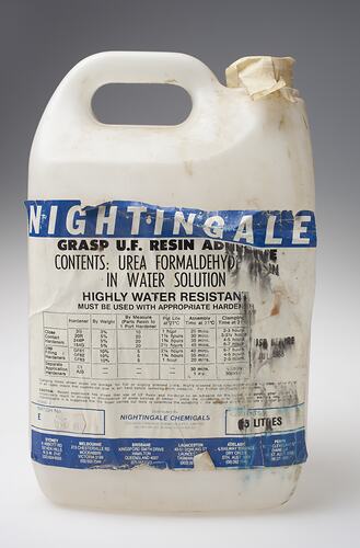 White dirty plastic bottle, white tape instead of lid. Damaged white label has blue and black printing.