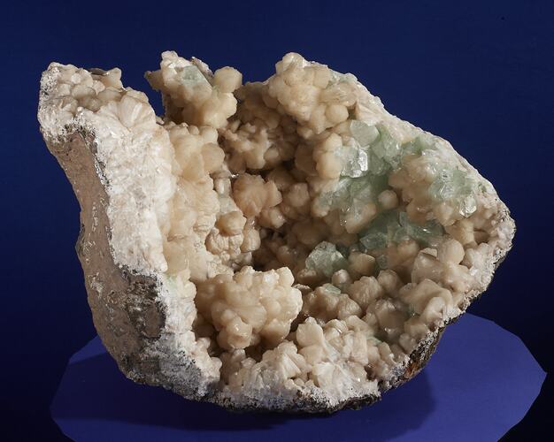 Rounded rock filled with cream and green crystals.