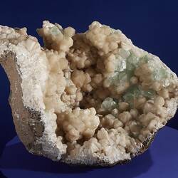 Rounded rock filled with cream and green crystals.