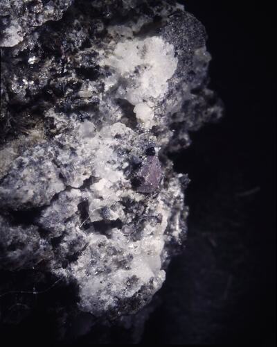 Chunky pink-purple crystal on white crystal surface.