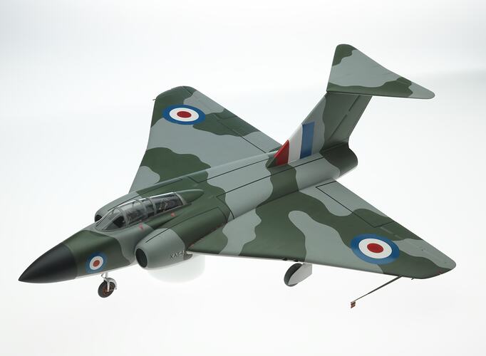 Wooden model grey and green camoflage aeroplane. Two air intakes at front and jets at rear. Black nose cone.