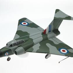 Wooden model grey and green camoflage aeroplane. Two air intakes at front and jets at rear. Black nose cone.