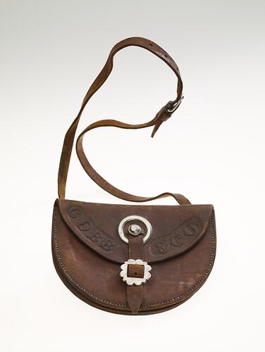 Semi-circular leather pouch with strap. Curved flap folds over pouch with leather strap and metal buckle.
