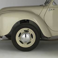 Cream coloured, two door motor car detail of front wheel arch.