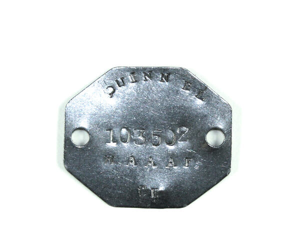Silver octagonal shaped metal tag with stamped text.